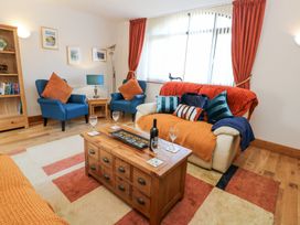 A living room with armchairs sofa coffee table and wine glasses at Rayson Hall Barns in Ousby
