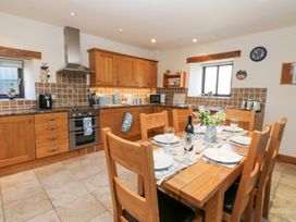 A kitchen with wooden cabinets and dining table set with plates and glasses at Rayson Hall Barns in Ousby