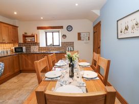 A kitchen with wooden cabinets a dining table set with plates glasses and a wine bottle at Rayson Hall Barns in Ousby