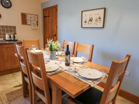 A wooden dining table set with plates glasses and a vase with flowers in a kitchen at Rayson Hall Barns in Ousby