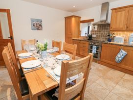 A kitchen with wooden cabinets dining table with plates glasses and flowers at Rayson Hall Barns in Ousby