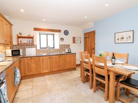 A kitchen with wooden cabinets a dining table set with plates glasses and a bottle at Rayson Hall Barns Ousby