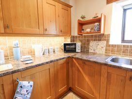 A kitchen corner with wooden cabinets a microwave kettle and utensils at Rayson Hall Barns Ousby