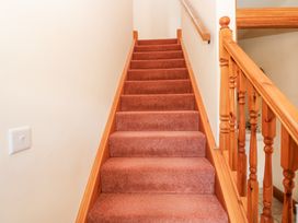 Carpeted staircase with wooden banister and handrail in a hallway at Rayson Hall Barns in Ousby