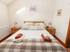 A bedroom with a double bed two bedside tables with lamps and folded towels at Rayson Hall Barns in Ousby