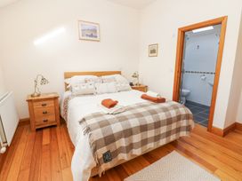 A bedroom with a double bed bedside tables lamps and an en suite bathroom at Rayson Hall Barns in Ousby