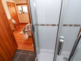 A shower with glass doors and chrome handles opening to a bedroom with wooden furniture at Rayson Hall Barns in Ousby