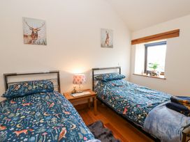 A bedroom with two single beds with animal-themed bedding a wooden nightstand with a lamp and animal figurines and a window with a plant on the sill at Rayson Hall Barns in Ousby