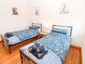 A bedroom with two single beds with blue patterned bedding and towels on wooden floor at Rayson Hall Barns in Ousby