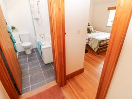 View of a bathroom with toilet bathtub and shower next to a bedroom with bed and window at Rayson Hall Barns in Ousby