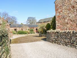 A courtyard with stone walls and gravel surrounded by stone buildings at Rayson Hall Barns in Ousby