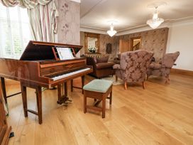 A living room with a piano and seating at Mount House Bryniau near Dyserth