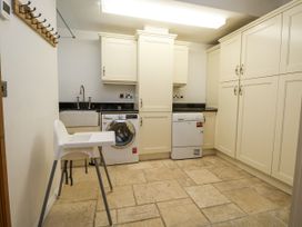 A laundry room with a washing machine, sink, and cupboards at Mount House Bryniau near Dyserth