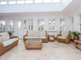 A conservatory with rattan furniture and glass windows at Mount House Bryniau near Dyserth