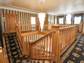 A staircase with wood railing and chandelier at Mount House Bryniau near Dyserth