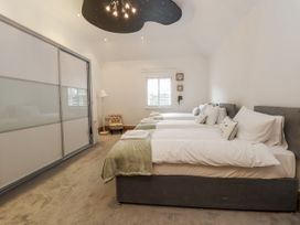 A bedroom with three beds and a wardrobe at Mount House Bryniau near Dyserth