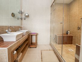 A bathroom with sinks, mirrors, shower and tub at Mount House Bryniau near Dyserth