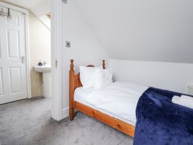 A bedroom with a single bed and a doorway leading to a bathroom at Mount House Bryniau near Dyserth