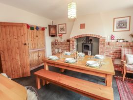 A dining room with a wooden table set for six and a brick fireplace at 2 High Lane Terrace in Kirkby Stephen