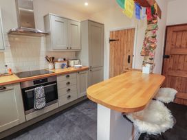 A kitchen with wooden countertops, cabinets, bar stools with fur covers, and wooden doors at 2 High Lane Terrace Kirkby Stephen