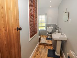 A bathroom with a pedestal sink a toilet a window with blinds and wooden flooring at 2 High Lane Terrace in Kirkby Stephen