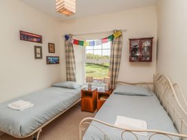 A bedroom with two single beds bedside tables with lamps and a window at 2 High Lane Terrace in Kirkby Stephen