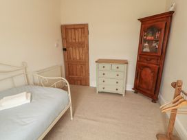 A bedroom with a white metal bed frame dresser wooden cabinet and wooden door at 2 High Lane Terrace in Kirkby Stephen