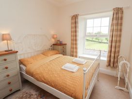 A bedroom with a metal bed frame two dressers bedside lamps and a window at 2 High Lane Terrace in Kirkby Stephen