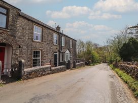 A stone house beside a narrow road with trees and stone walls at 2 High Lane Terrace in Kirkby Stephen