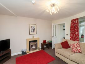 A living room with a beige sofa and red cushions a red rug a television and a fireplace at Counting House in Bridlington