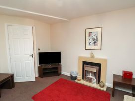 A room with a television on a stand a fireplace with decorations a red rug and a side table with a red box at Counting House in Bridlington
