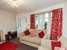 A living room with beige sofas red and patterned cushions red patterned curtains and a red rug at Counting House in Bridlington