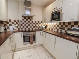 A kitchen with white cabinets checkered backsplash and appliances at Counting House in Bridlington
