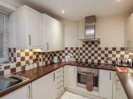 A kitchen with white cabinets brown countertops checkered tile backsplash and stainless steel oven at Counting House Bridlington