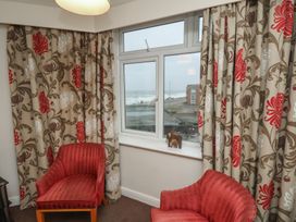 Two red armchairs near a window with floral curtains and a view outside at Counting House in Bridlington