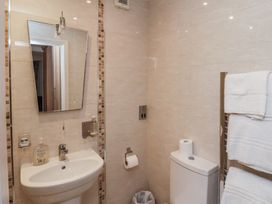 A bathroom with a sink mirror toilet paper holder trash bin and towel rack at Counting House in Bridlington
