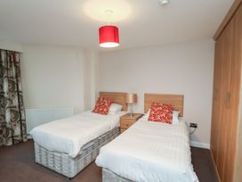 A bedroom with two single beds a nightstand with a lamp a wardrobe and patterned curtains at Counting House Bridlington