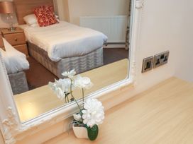 A bedroom with single beds and a bedside table reflected in a mirror with white flowers on a wooden surface at Counting House Bridlington