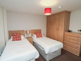 A bedroom with two single beds a bedside table with a lamp a wardrobe and a chest of drawers at Counting House in Bridlington