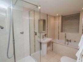A bathroom with a shower, a pedestal sink, a bathtub, and a window with blinds at Counting House in Bridlington