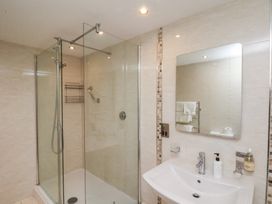 A bathroom with a glass shower enclosure and a white sink with a mirror at Counting House in Bridlington
