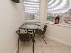 A corner with a glass table and two wicker chairs by windows with blinds and a red lantern on the windowsill at Counting House in Bridlington