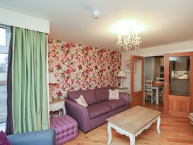 A living room with a purple sofa floral wallpaper white coffee table and a chandelier at Secret Garden in Bridlington