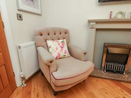 An armchair with a floral pillow beside a radiator and fireplace at Secret Garden in Bridlington