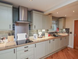 A kitchen with white cabinets wooden countertops a stainless steel stove and hood a kettle and a sink at Secret Garden in Bridlington