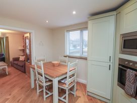 A kitchen dining area with a wooden table and four chairs with a window and built in appliances at Secret Garden in Bridlington