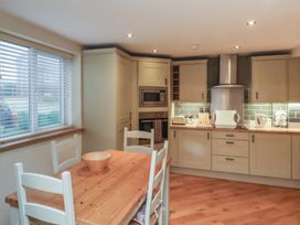 A kitchen with wooden table and chairs next to window and cabinets with appliances at Secret Garden in Bridlington