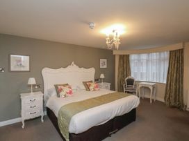 A bedroom with a large bed two nightstands lamps a chair and a table at Secret Garden in Bridlington