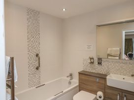 A bathroom with a bathtub a sink with vanity unit and a large mirror at Secret Garden in Bridlington