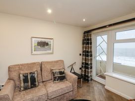 A living room with a beige sofa and pillows a telescope and glass door with ocean view at Lookout Post in Bridlington